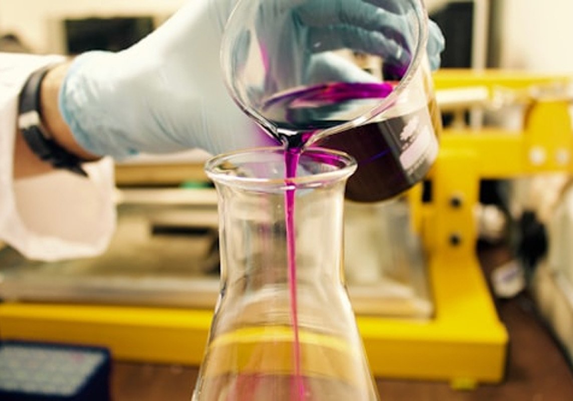 Chemist pouring a sample into a flask in the laboratory